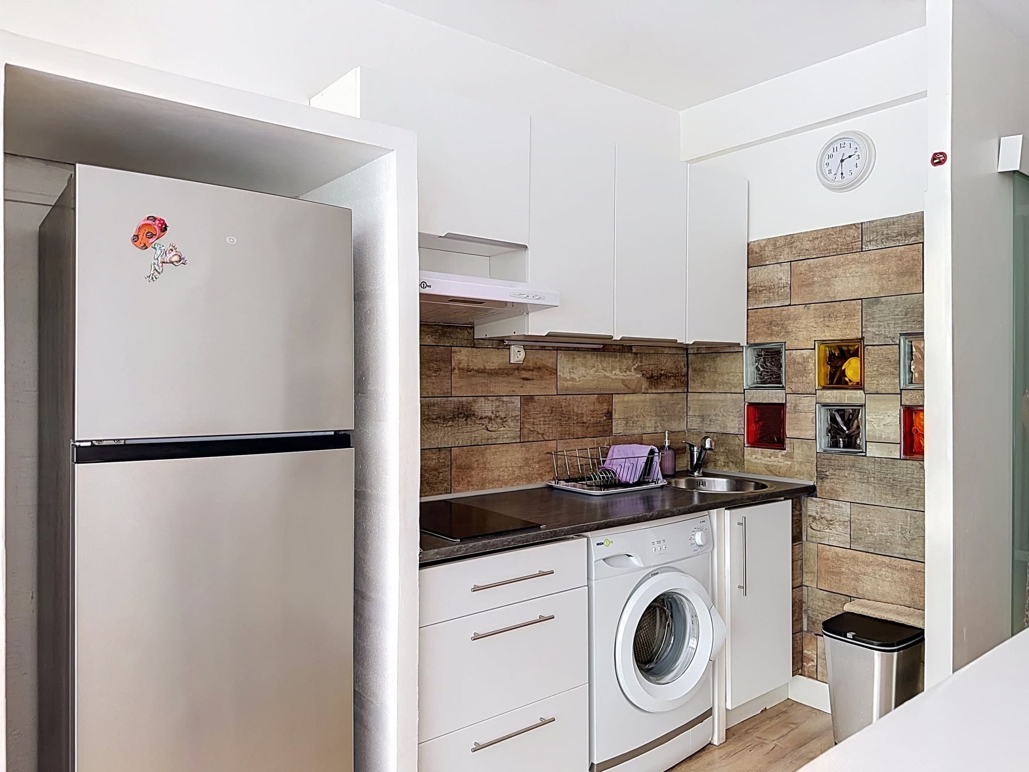 La cuisine équipée : réfrigérateur, plaques de cuisson, évier et lave-linge