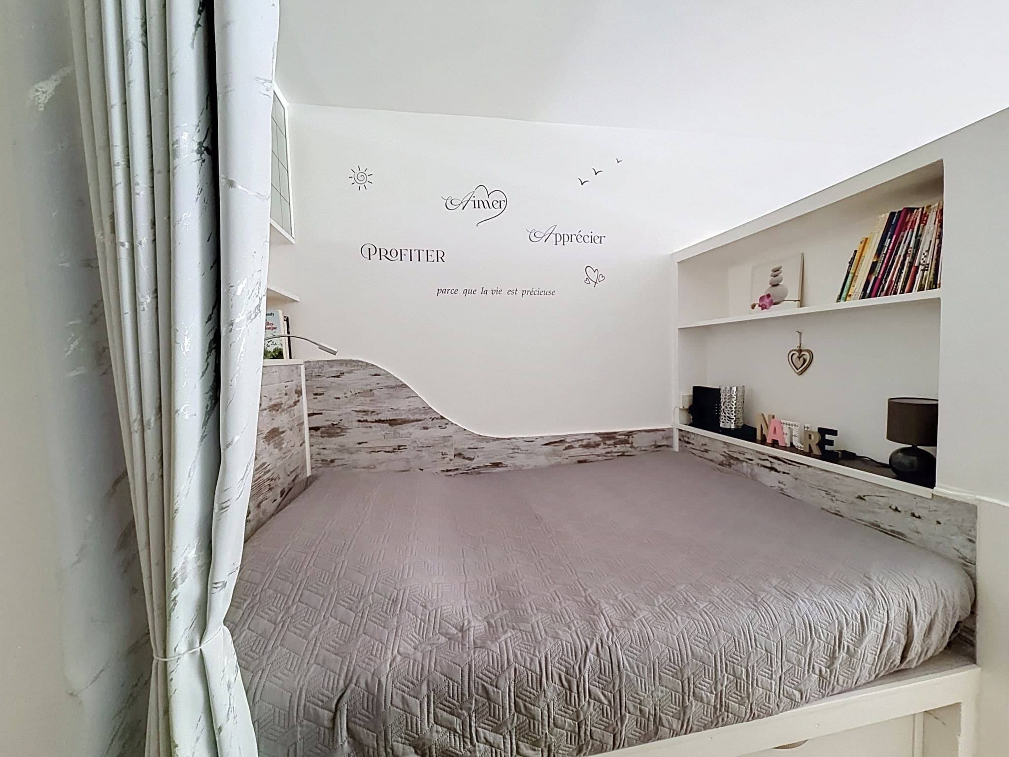 Le lit double du coin nuit, dans son alcôve, sous les étagères de la tête de lit