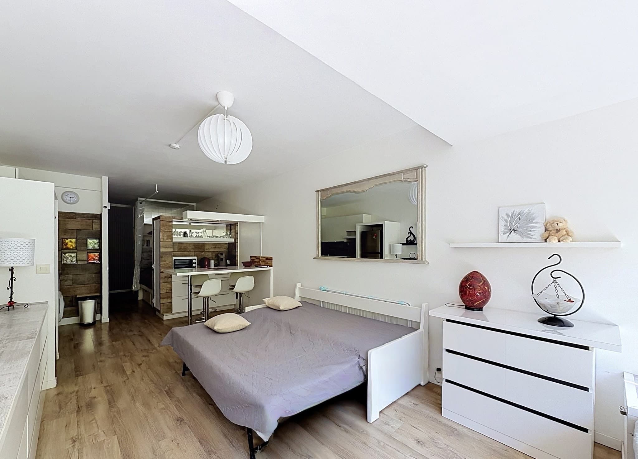 La pièce principale, le couchage ouvert, la commode et le bar au fond