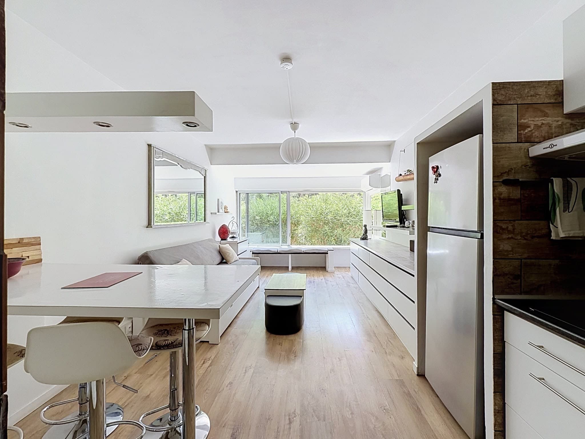 Le studio dans sa longueur, du bar au séjour et à la baie vitrée, la cuisine à droite