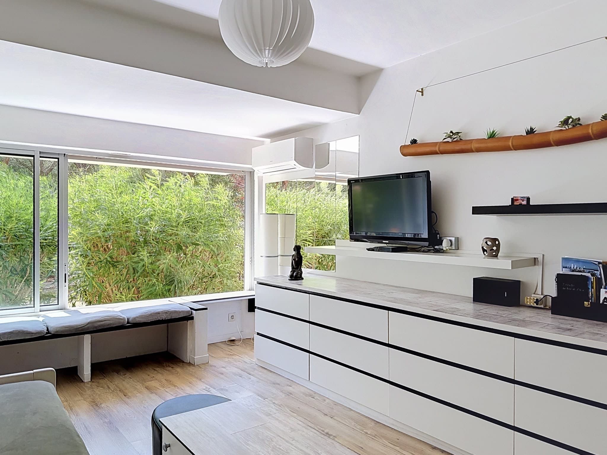 Le coin télévision, son long meuble bas et la banquette sous la baie vitrée